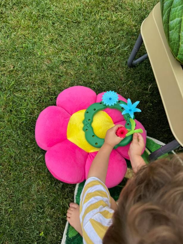 Criança encaixando peças coloridas em um brinquedo sensorial em forma de flor