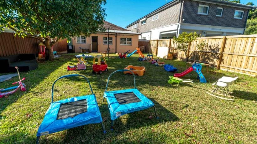 Quintal gramado do Family Day Care, com brinquedos, escorregadores e trampolins