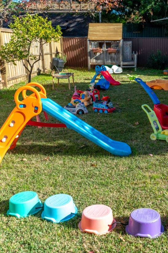 Quintal do Family Day Care montado com escorregador, brinquedos e casinha de madeira